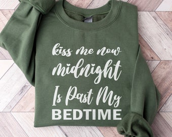 Op de afbeelding: Groen sweatshirt met de tekst "kiss me now midnight is past my bedtime" in wit.