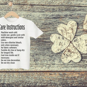 Peut inclure: T-shirt blanc avec des instructions d'entretien imprim&eacute;es dessus. Les instructions comprennent un lavage en machine &agrave; froid, &agrave; l'envers, un cycle d&eacute;licat avec un d&eacute;tergent doux et des couleurs similaires. Utiliser de l'eau de Javel non chlor&eacute;e uniquement si n&eacute;cessaire. Pas d'adoucissant. S&eacute;cher en machine &agrave; basse temp&eacute;rature ou suspendre pour s&eacute;cher afin de prolonger la dur&eacute;e de vie. Repasser &agrave; froid &agrave; l'envers si n&eacute;cessaire. Ne pas repasser la d&eacute;coration. Ne pas nettoyer &agrave; sec.
