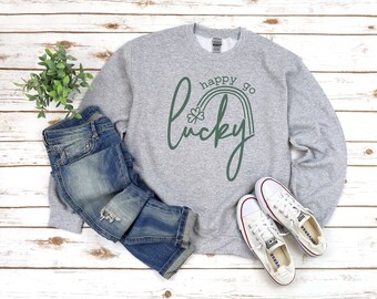 May include: A gray sweatshirt with the text "happy go lucky" in green script with a rainbow and shamrock design.