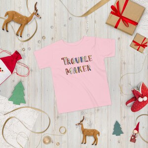 May include: Pink toddler t-shirt with the words "Trouble Maker" in colorful letters.