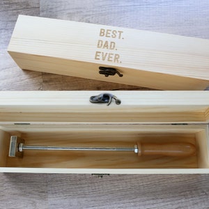May include: A wooden box with a hinged lid and a metal latch. The box is open and contains a wooden dowel with a metal handle. The box is engraved with the text "BEST. DAD. EVER."