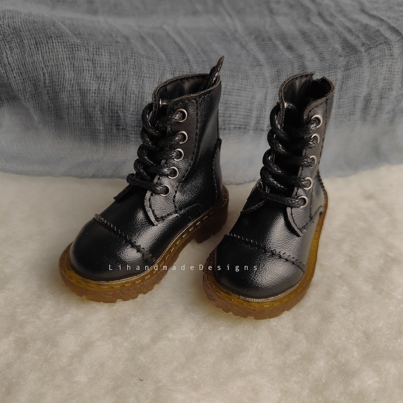 May include: A pair of black leather ankle boots with laces and a thick rubber sole. The boots have a classic style and are perfect for everyday wear.