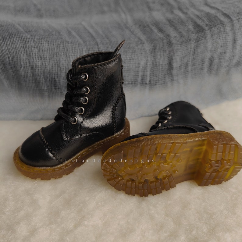 May include: A pair of black leather ankle boots with laces and a thick rubber sole. The boots have a classic style and are perfect for everyday wear.
