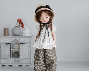 Handgefertigtes Puppenoutfit, weiße Bluse mit Puffärmeln und weite Hose mit Gänseblümchenmuster,