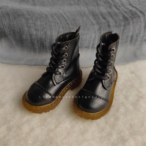 May include: A pair of black leather ankle boots with laces and a brown rubber sole.