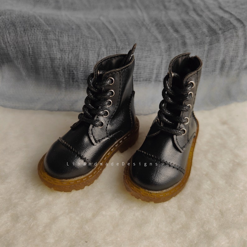 May include: A pair of black leather ankle boots with laces and a brown rubber sole.