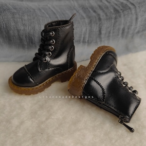 May include: A pair of black leather boots with laces and a zipper on the side. The boots have a brown rubber sole.