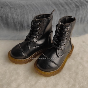 May include: A pair of black leather lace-up boots with a brown rubber sole. The boots have a classic style and are perfect for everyday wear.