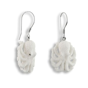 May include: A pair of white ceramic octopus earrings with silver hooks. The octopus is detailed with a textured surface and has eight tentacles.