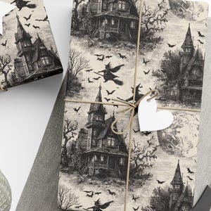 Vintage Halloween wrapping paper featuring haunted houses, flying bats, and full moon on an aged parchment cream background, tied with twine and heart tag