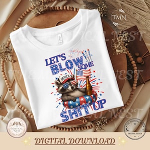 Patriotic "Let's Blow Some Shit Up" design displayed on a white t-shirt mockup featuring a raccoon wearing American flag sunglasses and a "Merica" hat, holding a drink in a red, white, and blue float with fireworks and American flag elements. Styled on a neutral boho background with wooden beads and dried florals. Bottom banner reads "Digital Download" with The Mystical Nest branding.
