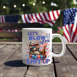 USA PNG image with a 4th of July theme digital download. The design features a cute racoon laying in a pool float holding a beer and an American flag with a hat that says merica. With red, white, and blue text that says lets blow some shit up, referring to fireworks. Same color fireworks surrounding image, perfect for Independence Day celebrations.