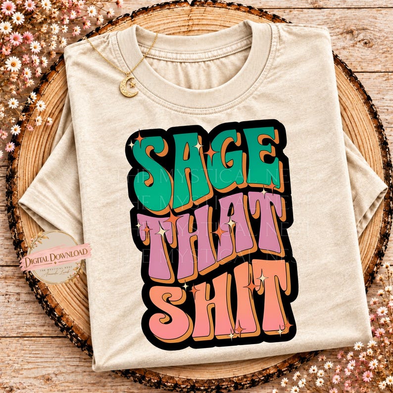 A beige t-shirt rests on a wooden surface with a colorful retro graphic that reads Sage That Shit.
