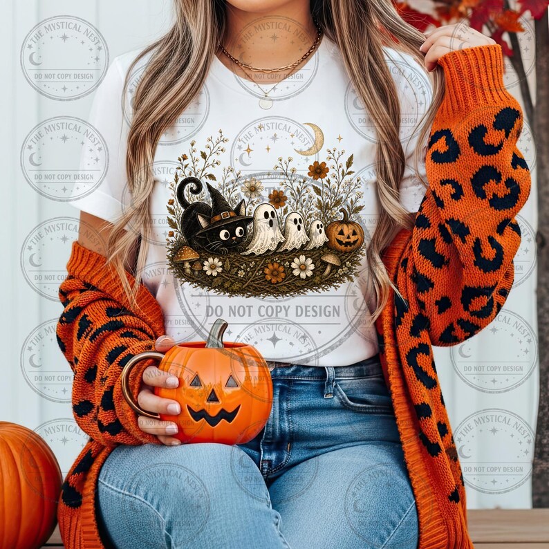 Woman wearing white t-shirt with cute black witch cat, friendly ghosts, jack o' lantern, moon, wildflowers, and cozy vintage Halloween sublimation design.