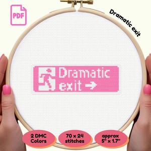 Peut inclure: Une broderie au point de croix dans un cercle en bois, avec les mots "Dramatic exit" en rose et blanc. Le motif comprend un symbole de personne en course et une flèche. Le texte mesure environ 12,7 cm x 4,3 cm et utilise 2 couleurs DMC.