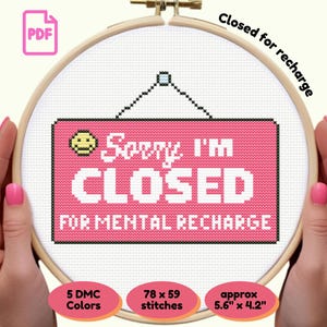 May include: Cross-stitch design in a wooden hoop, featuring a pink sign that reads "Sorry I'm CLOSED FOR MENTAL RECHARGE." Includes a smiley face and details about the 5 DMC colours, 78 x 59 stitches, and approximate size of 14.2cm x 10.7cm.