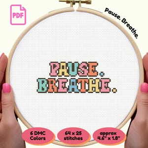May include: A cross-stitch project in a wooden hoop, featuring the words "PAUSE. BREATHE." in colorful letters. The design includes 6 DMC colors and measures approximately 4.6" x 1.8". The image also includes a PDF icon.
