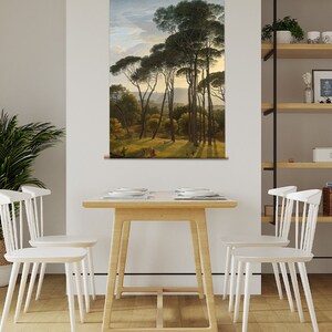May include: A painting of a forest scene with tall pine trees and a path leading through the trees. The painting is framed and hanging on a wall in a room with a wooden table and white chairs.
