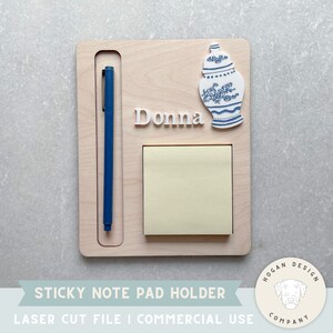 May include: A wooden sticky note pad holder featuring a blue and white ceramic jar design. The holder has a slot for a pen and a space for a sticky note pad. The name "Donna" is engraved on the holder.