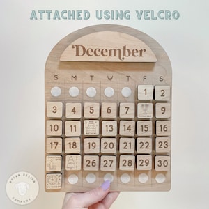 May include: Wooden calendar with removable blocks for each day of December. The calendar features a variety of holidays including Hanukkah, a birthday, Christmas Eve, and New Year's Eve.