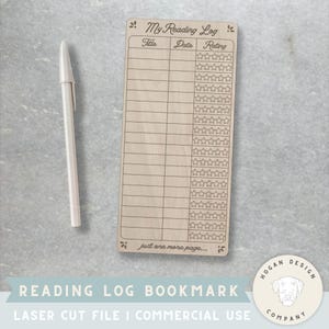May include: A wooden reading log bookmark with the text "My Reading Log" and spaces to record book titles, dates, and ratings. A white pen rests beside the bookmark. The bookmark has the text "just one more page...." at the bottom.