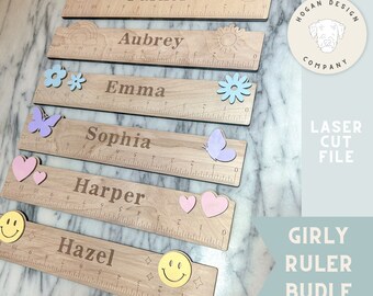 May include: A set of six wooden rulers with personalized names and decorative elements. The rulers feature a rainbow, a sun, a flower, a butterfly, a heart, and a smiley face. Each ruler is 12 inches long.