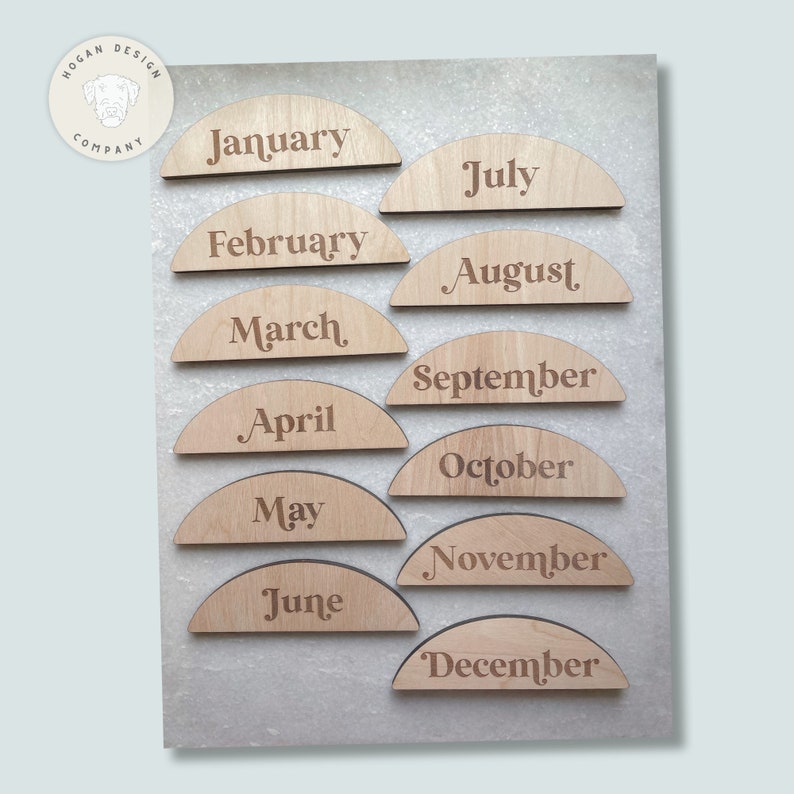 May include: Twelve wooden half-circle pieces with the months of the year engraved on them. The pieces are arranged in a semi-circle, with January at the top and December at the bottom.