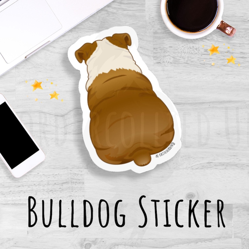 May include: A sticker featuring a brown and white bulldog from the rear. The sticker has a white border and the text "BULLDOG STICKER" in black. The sticker is on a light wood-grain surface.