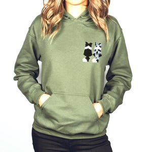 May include: A green hooded sweatshirt with a black and white graphic of two dogs on the front.