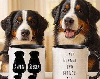 Peut inclure: Deux mugs en céramique blanche avec des poignées et des bords noirs. L'un des mugs présente des silhouettes de deux chiens avec les noms "Aspen" et "Sierra". L'autre mug porte le texte "I WAS NORMAL TWO BERNERS AGO."