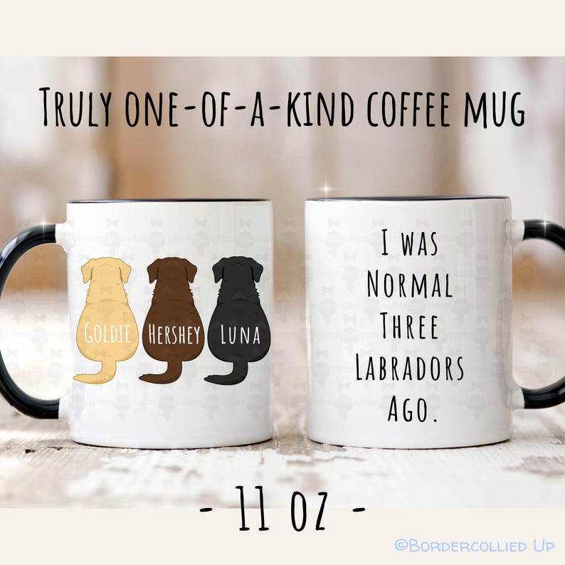 May include: White coffee mug with black handle and rim. The mug features three Labrador illustrations in yellow, brown, and black, each with a name. Text reads "TRULY ONE-OF-A-KIND COFFEE MUG" and "I WAS NORMAL THREE LABRADORS AGO." The mug is 11 oz.
