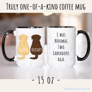 May include: White coffee mug with black handle and rim. The mug features two Labrador silhouettes, one tan and one brown, with the names "Goldie" and "Hershey". The other side reads "I WAS NORMAL TWO LABRADORS AGO." The mug is 15 oz.