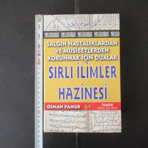 Puede incluir: Un libro amarillo con el título "SIRLI İLİMLER HAZİNESİ" en letras azules. La portada del libro también incluye el texto "SALGIN HASTALIKLARDAN VE MUSİBETLERDEN KORUNMAK İÇİN DUALAR" en letras negras. El libro es de Osman Pamuk.