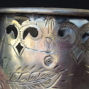 May include: Silver cup with an intricate design of floral patterns and a decorative border. The cup has a silver hallmark.