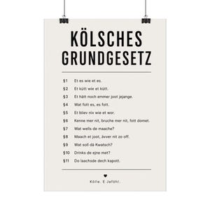 Könnte beinhalten: Ein vertikales Wandplakat mit dem schwarzen Text KÖLSCHES GRUNDGESETZ oben, gefolgt von elf nummerierten Abschnitten in Kölscher Mundart, das unten mit einem kleinen Herzsymbol und dem Text Kölle. E Jeföhl. abgeschlossen wird.