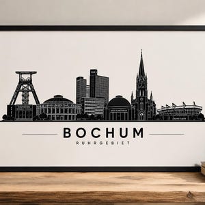 Könnte beinhalten: Schwarz-Weiß-Druck mit Rahmen, der die Skyline von Bochum zeigt. Der Druck enthält den Namen der Stadt und Ruhrgebiet darunter. Das Bild zeigt bemerkenswerte Gebäude und Strukturen, darunter eine Kirche und ein Stadion.