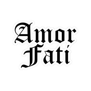 May include: A white sticker with the words "Amor Fati" in black gothic script. The phrase is centered and the letters are bold and stylized.