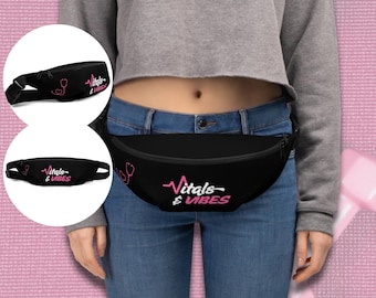 Może przedstawiać: Czarna saszetka biodrowa z różowym napisem "Vitals & Vibes" oraz grafiką stetoskopu. Torba jest noszona wokół talii i ma regulowany pasek. Na zdjęciu widoczna jest również mniejsza wersja saszetki.