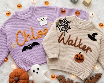 May include: A lavender knit sweater with the name Chloe in orange yarn, a white ghost, and a black bat, alongside a beige knit sweater with the name Walker in brown yarn, a black spiderweb, a black witch hat, and an orange jack-o'-lantern.