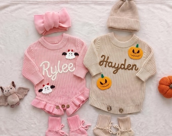 May include: A pink knit romper with the name Rylee, a matching pink bow headband, and pink booties. A beige knit sweater with the name Hayden, two pumpkin appliques, a matching beige beanie, and beige booties. A small plush bat and pumpkin.