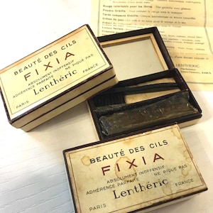 Op de afbeelding: Vintage Lenthéric FIXIA oogmake-up kits. De beige dozen met bruine randen hebben de tekst "BEAUTÉ DES CILS FIXIA" in bruin. De kits bevatten applicators en een spiegel. De tekst "FRANCE" is ook zichtbaar.