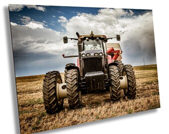 May include: A large red and black tractor with oversized tires is parked in a harvested field under a cloudy sky. The agricultural machine has a detailed design, with visible lights, mirrors, and a cab. The scene captures a rural landscape.