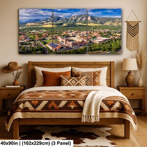 May include: A three-panel canvas print depicting a scenic aerial view of a city nestled at the base of a mountain range under a blue sky. The print is displayed above a wooden bed with decorative pillows and a patterned blanket. The dimensions are 40x90in.