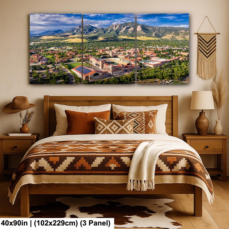 May include: A three-panel canvas print depicting a scenic aerial view of a city nestled at the base of a mountain range under a blue sky. The print is displayed above a wooden bed with decorative pillows and a patterned blanket. The dimensions are 40x90in.