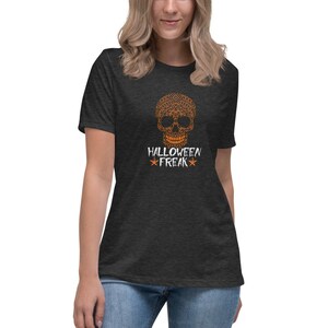 Puede incluir: Una camiseta gris oscuro jaspeada con un gráfico de calavera negra y naranja y el texto "Halloween Freak" en blanco con estrellas naranjas.