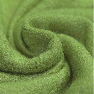 Könnte beinhalten: Nahaufnahme eines weichen, grünen Stoffes mit einer strukturierten Oberfläche. Der Stoff ist gefaltet und drapiert und zeigt seine Textur und Farbe.