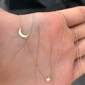 May include: A delicate gold chain necklace with a crescent moon charm and a small star charm.
