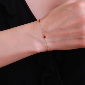 May include: A gold chain bracelet with red heart-shaped charms.
