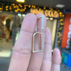 Könnte beinhalten: Goldene quadratische Creolen mit einem strukturierten Diamantenmuster.