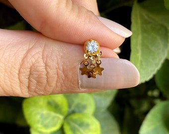 May include: Gold nose ring with a clear stone and dangling star charms.